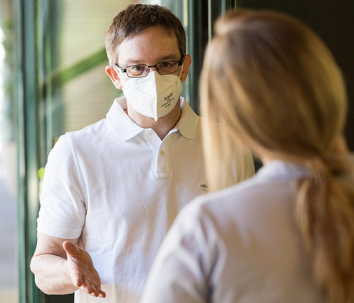 Ein Mann mit einer FFP2-Maske bietet ein Beratungsgespräch vor einer Impfungen an.