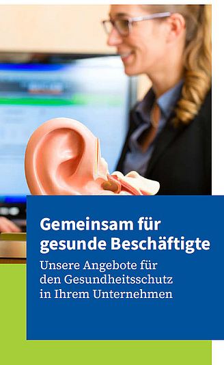Titelbild des AMD-Imageflyers: Eine Arbeitsmedizinerin betrachtet ein großes Ohrmodell am Schreibtisch.
