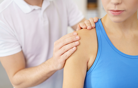 Eine Physiotherapeutin behandelt eine Patientin an der Schulter.